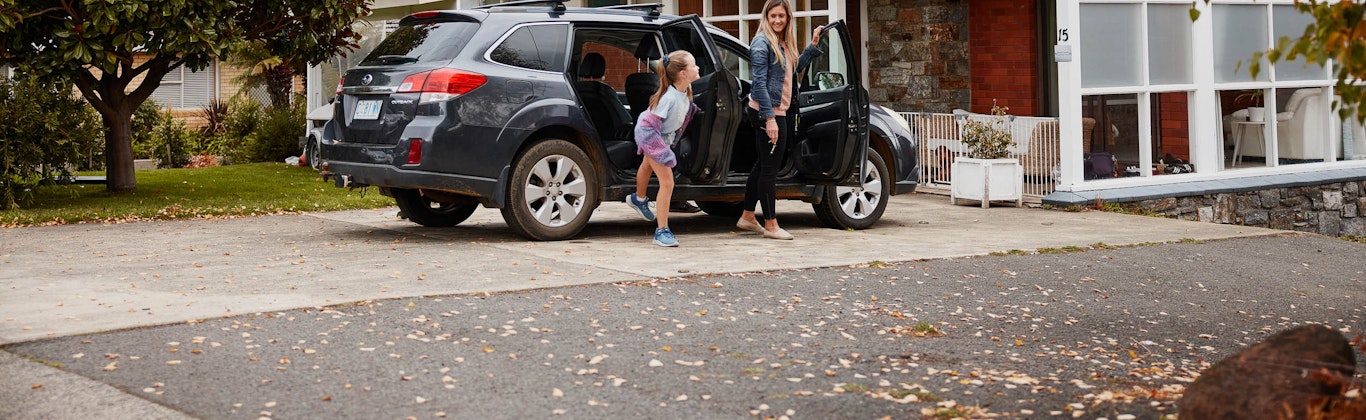 Mum and daughter getting out of the car outside their home