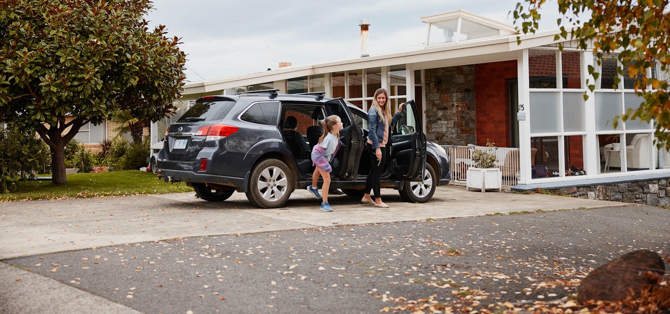 Mum and daughter getting out of the car outside their home