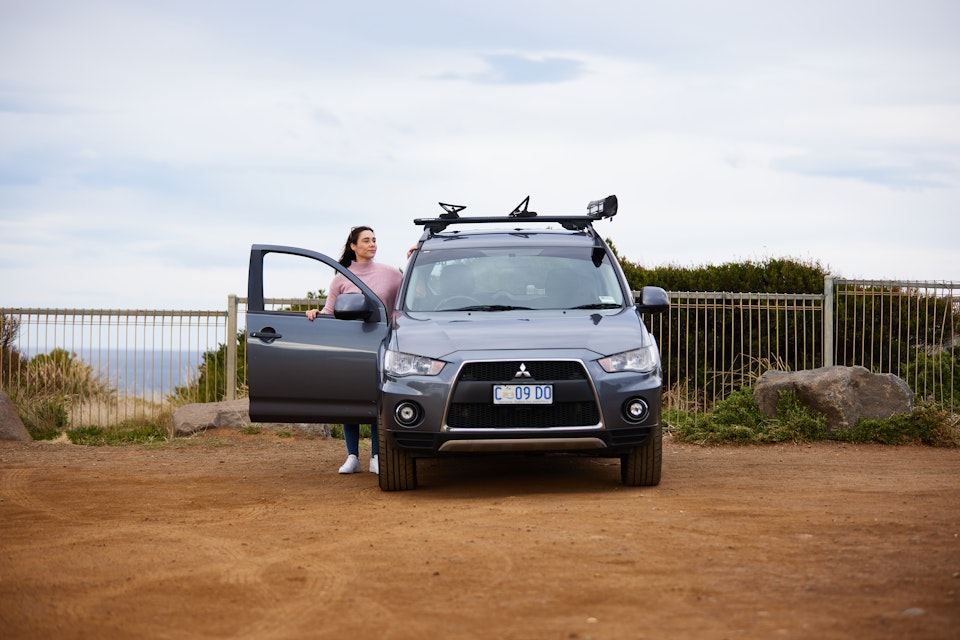 Woman at beach in car park next to her car