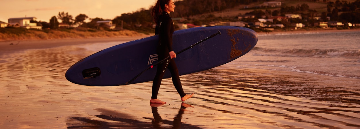 Surfer carrying surfboard into the ocean