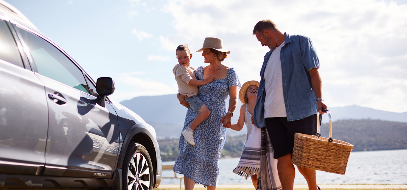Family standing next to the car in front of the beach