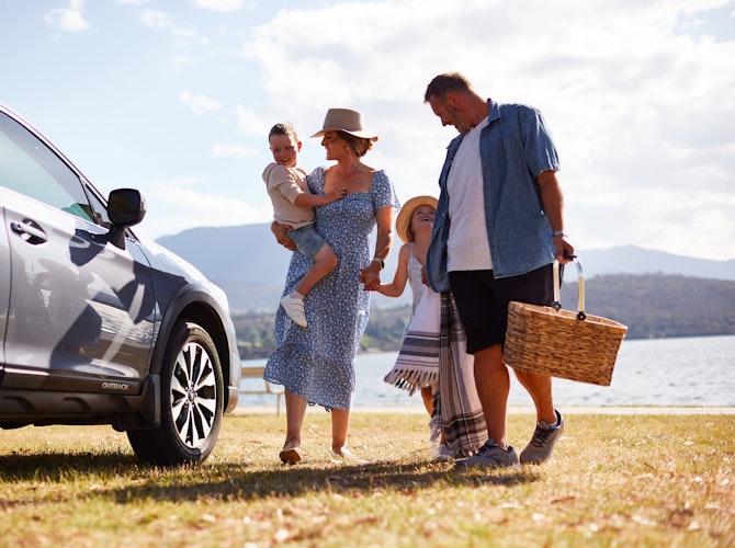 Family standing next to the car in front of the beach