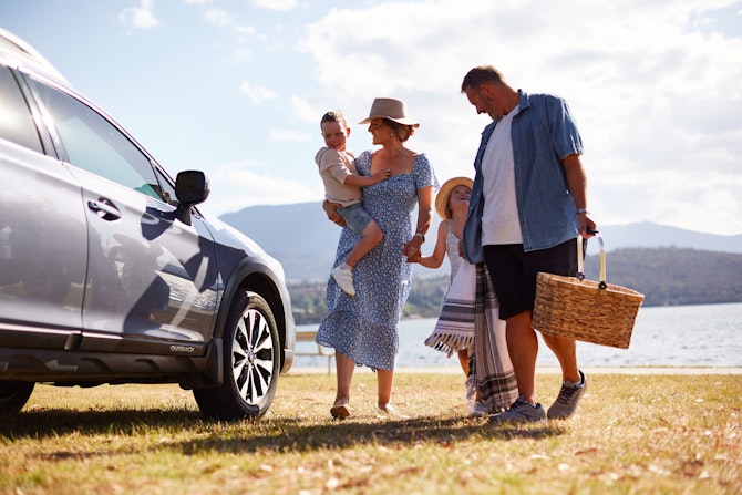 Family standing next to the car in front of the beach