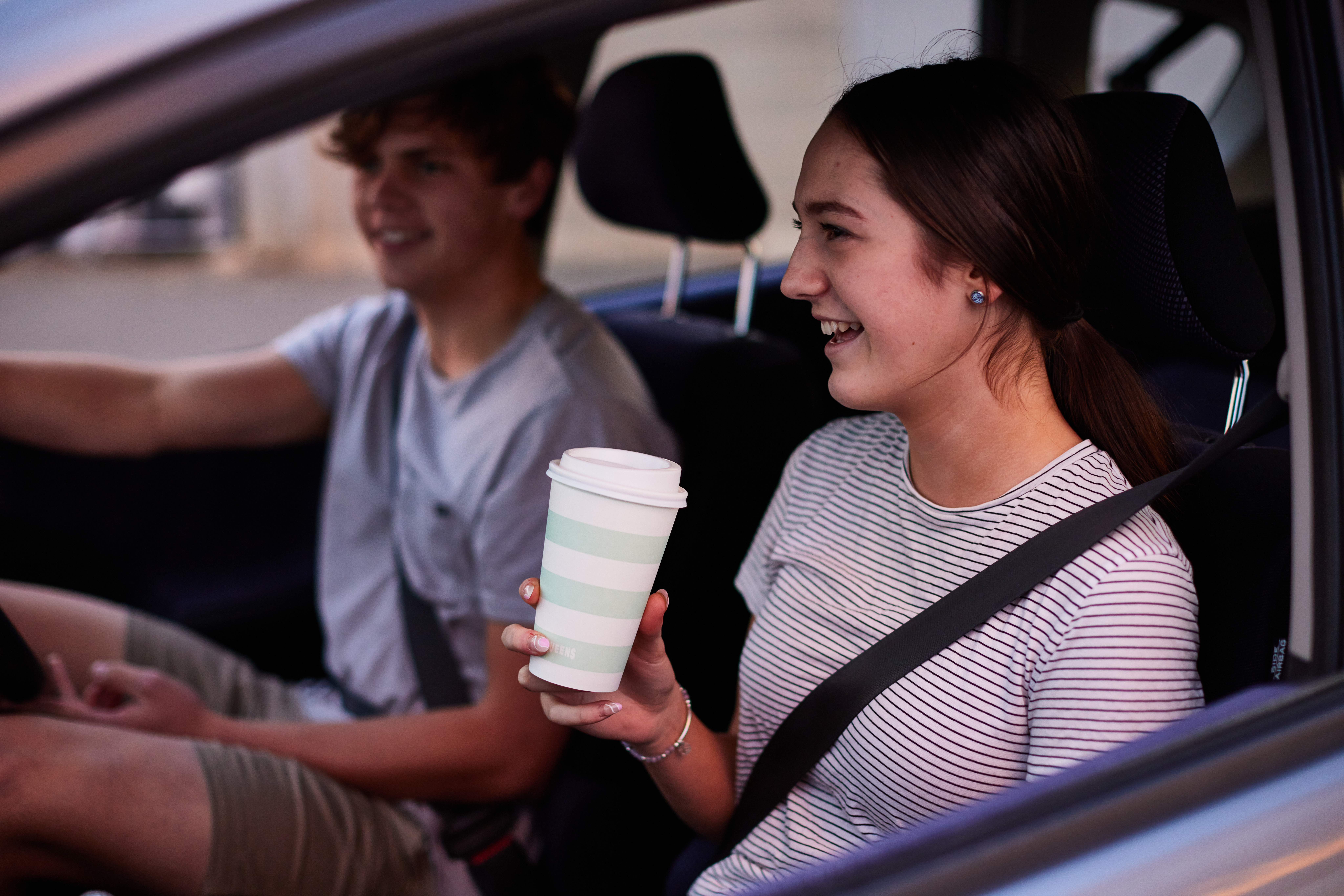 Young adults driving a car with coffee