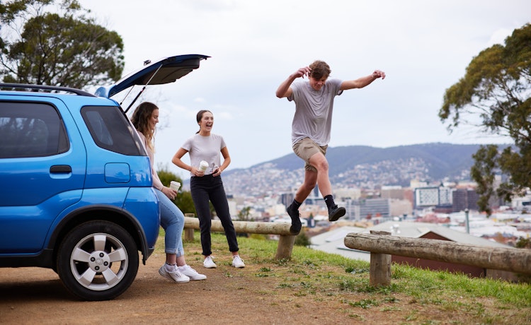Young adults playing near a car