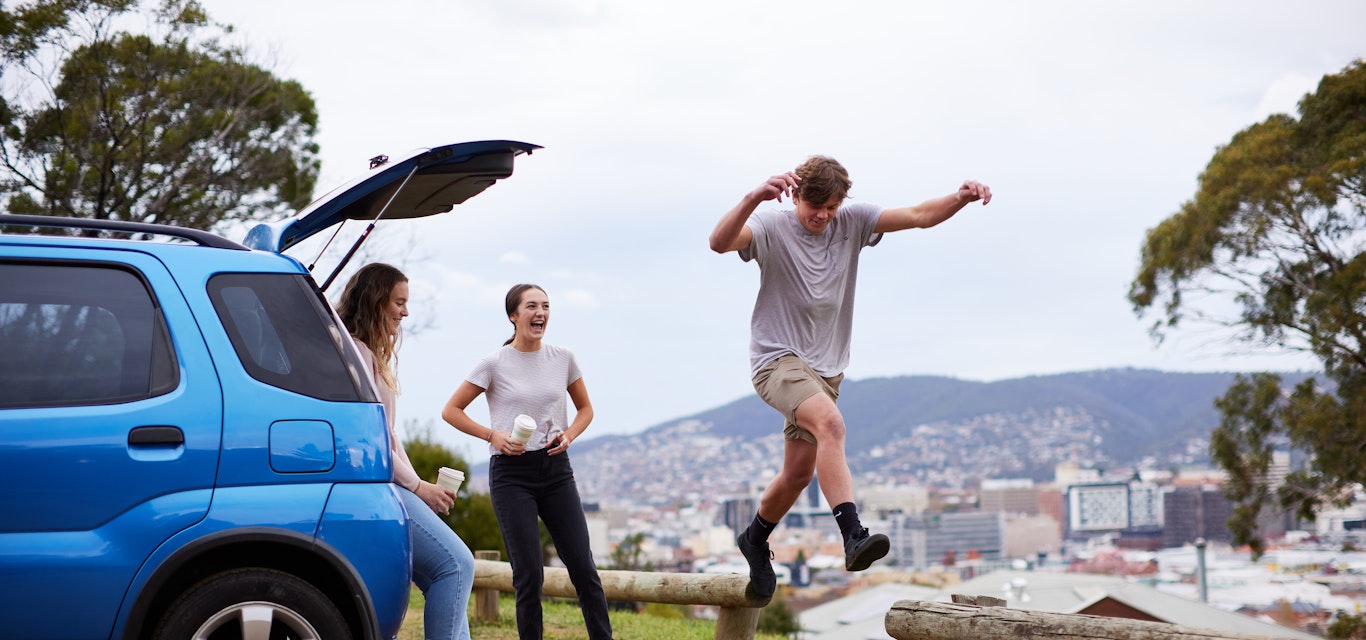 Young adults playing near a car