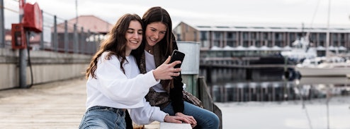 Two teenage girls looking at a mobile phone