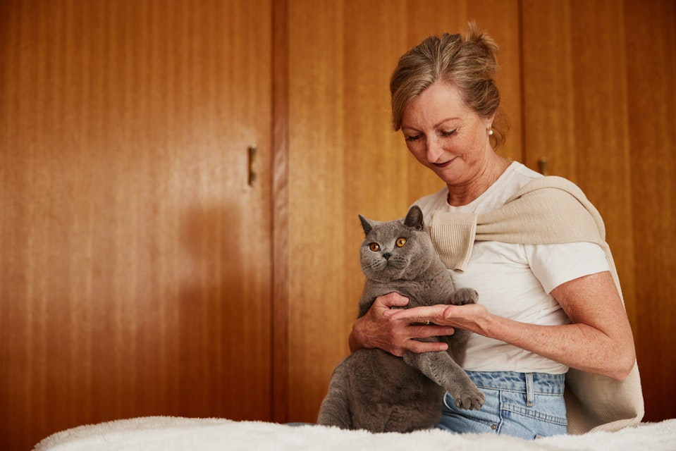 Woman holding a cat on the bed