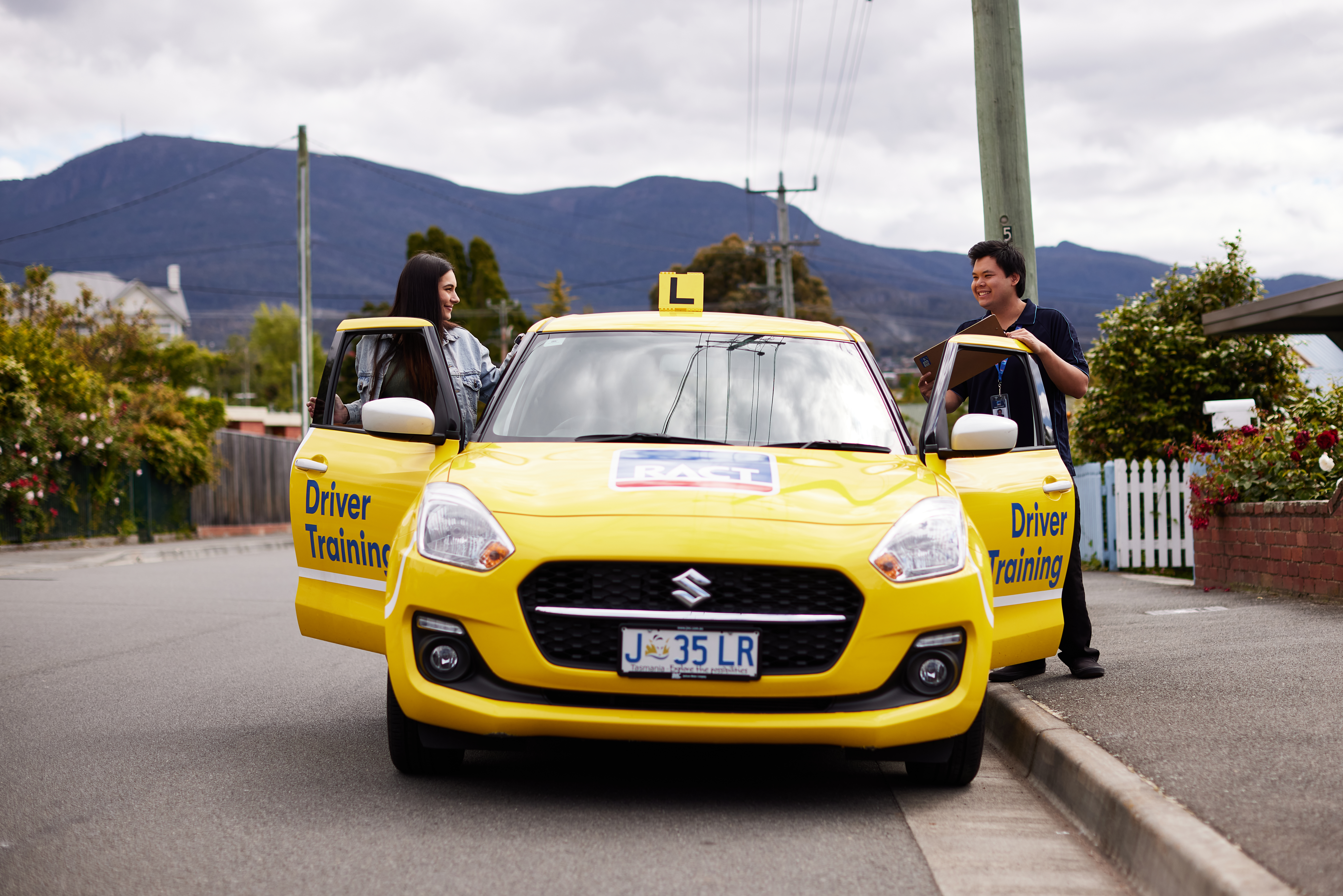 Driving student and instructor standing beside car