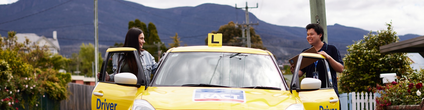 Driving student and instructor standing beside car