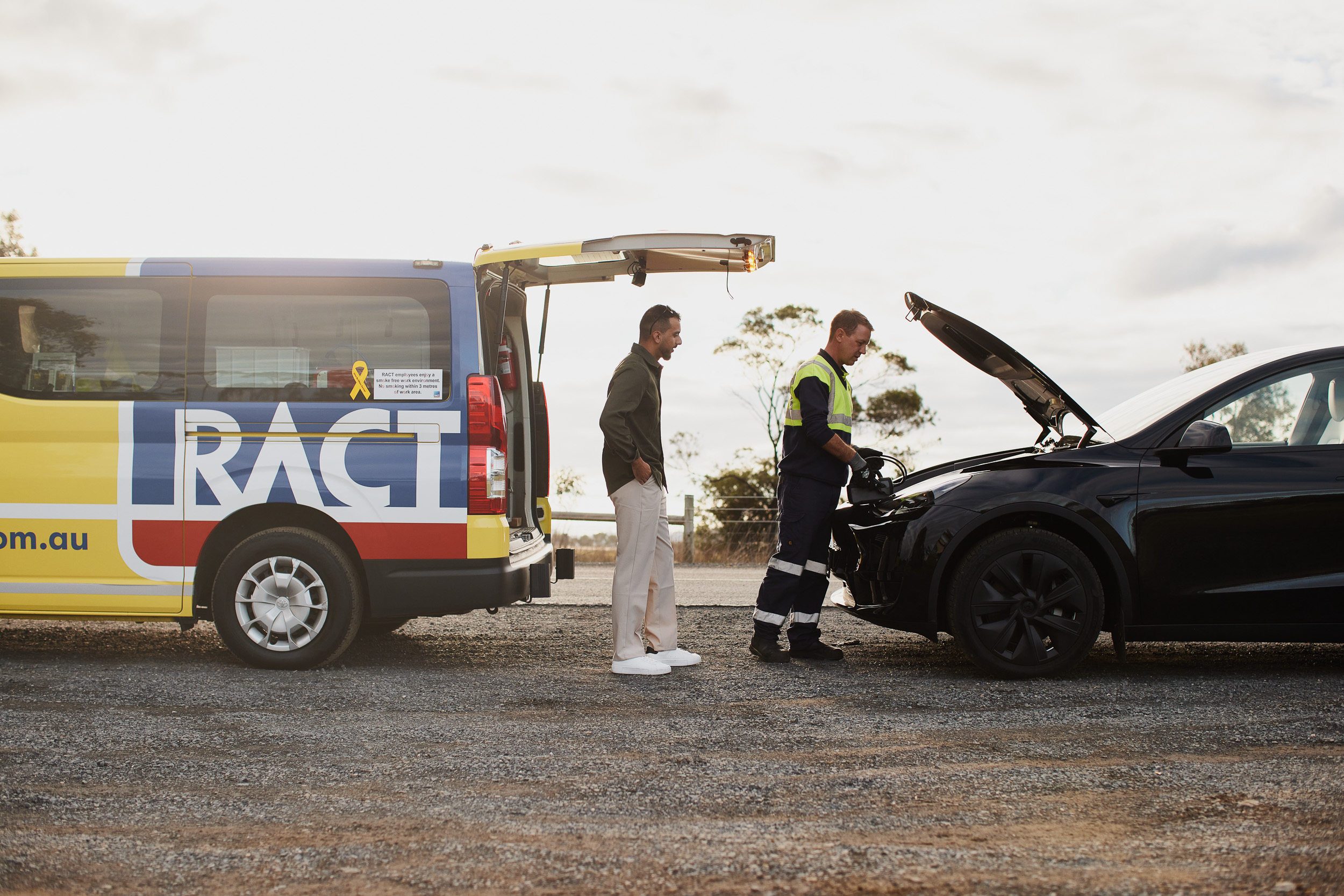 Member and roadside patrol on the side of the road looking at broken down EV car