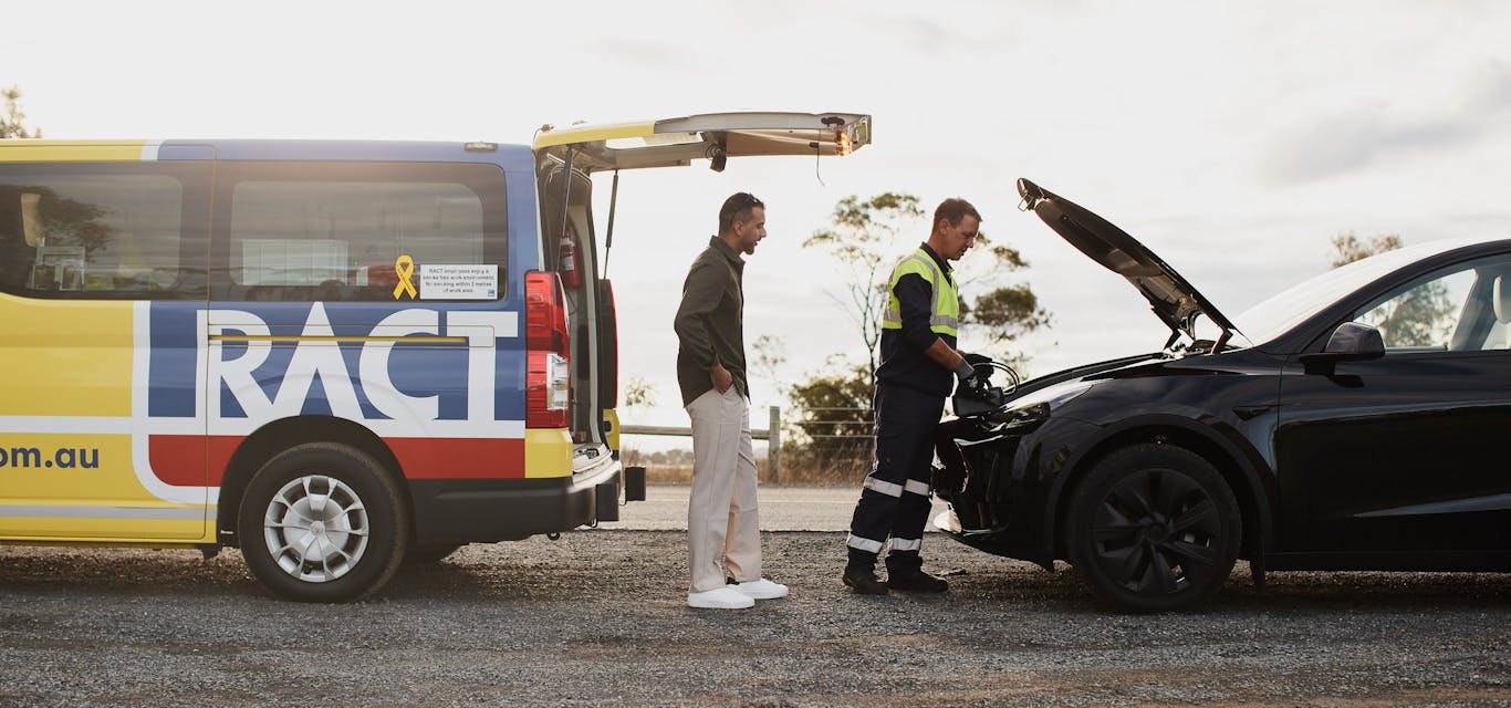 Member and roadside patrol on the side of the road looking at broken down EV car