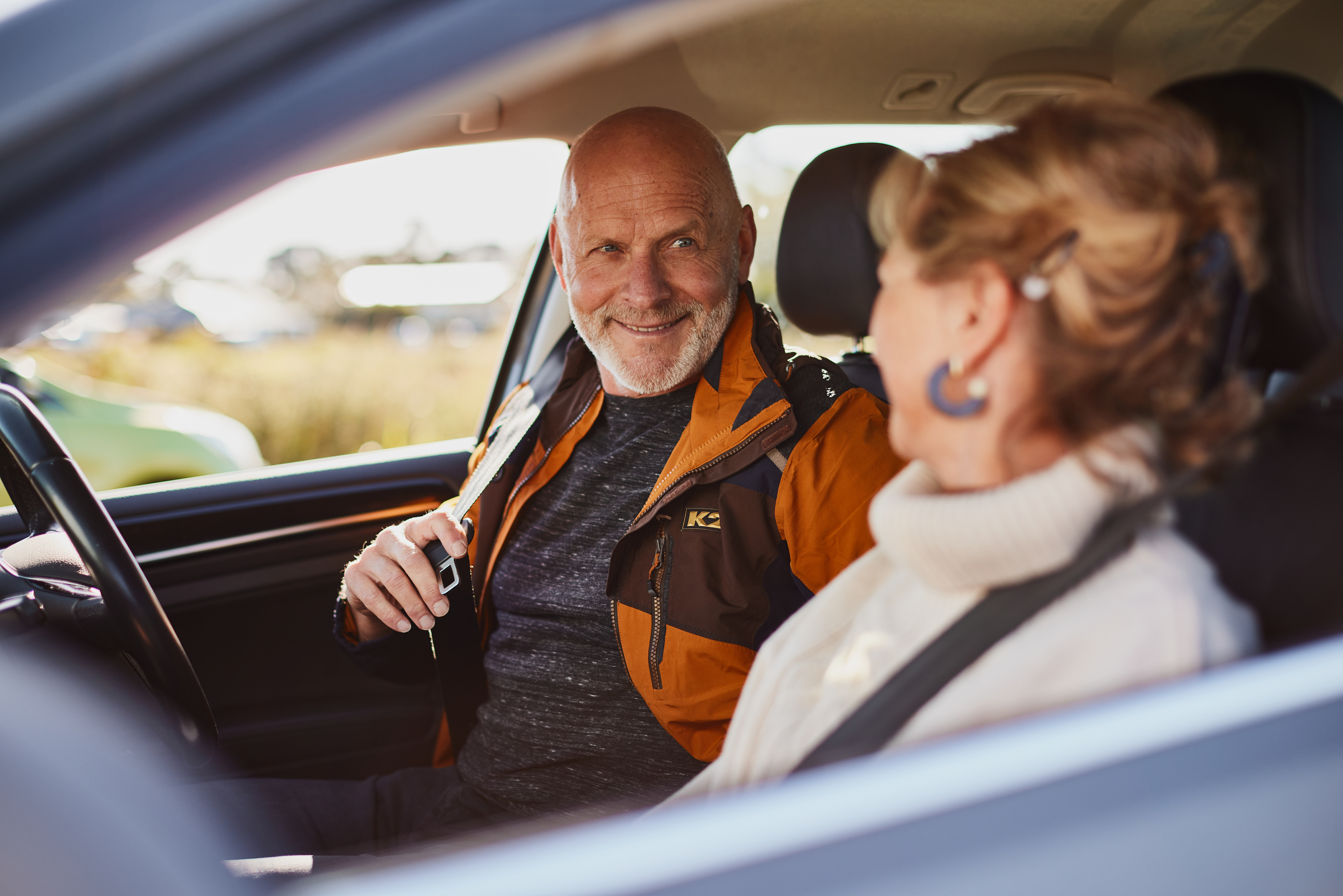 Senior couple sitting in the car putting seat belts on