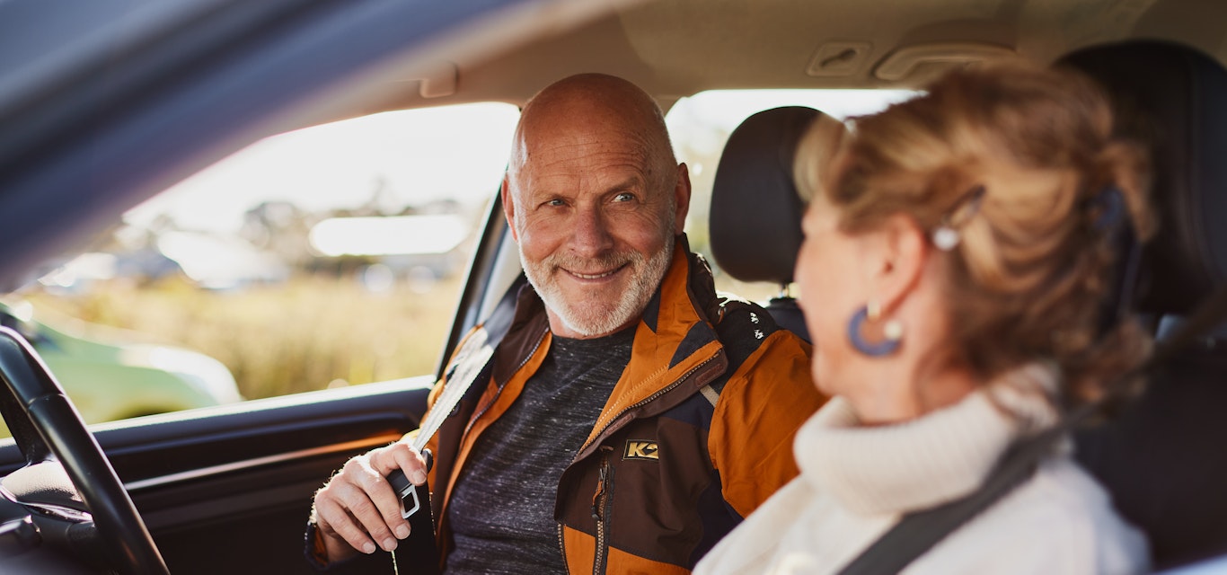 Senior couple sitting in the car putting seat belts on