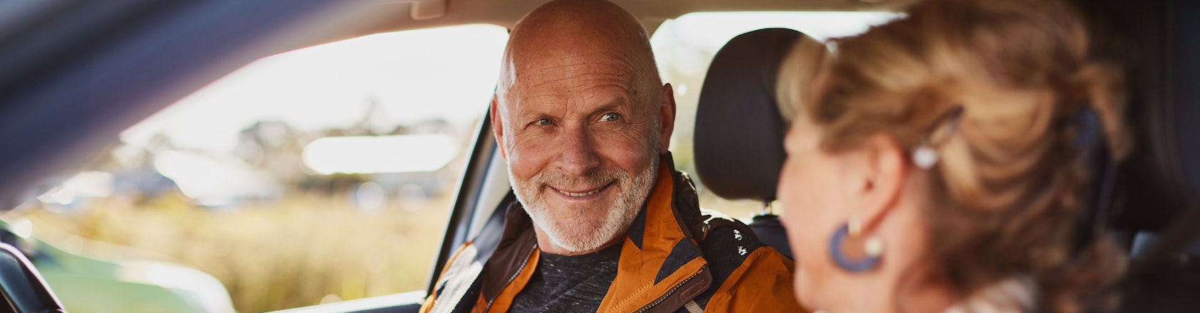 Senior couple sitting in the car putting seat belts on