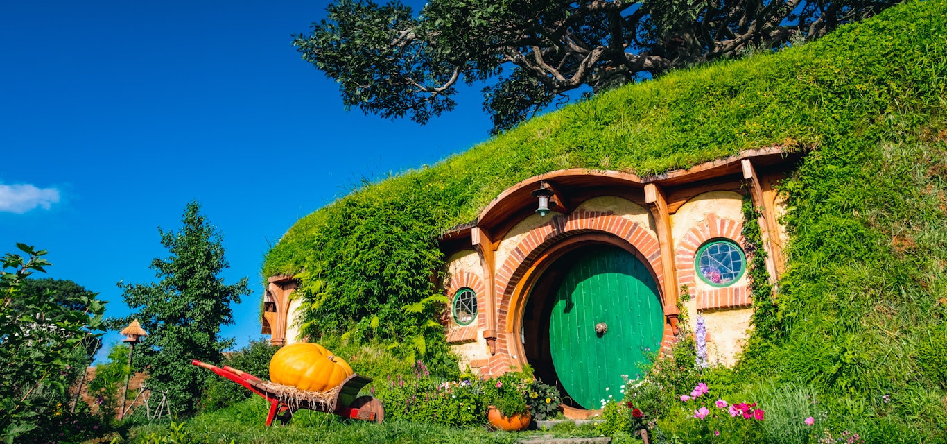 Hobbiton film set, with doorway in hill and pumpkin outside.