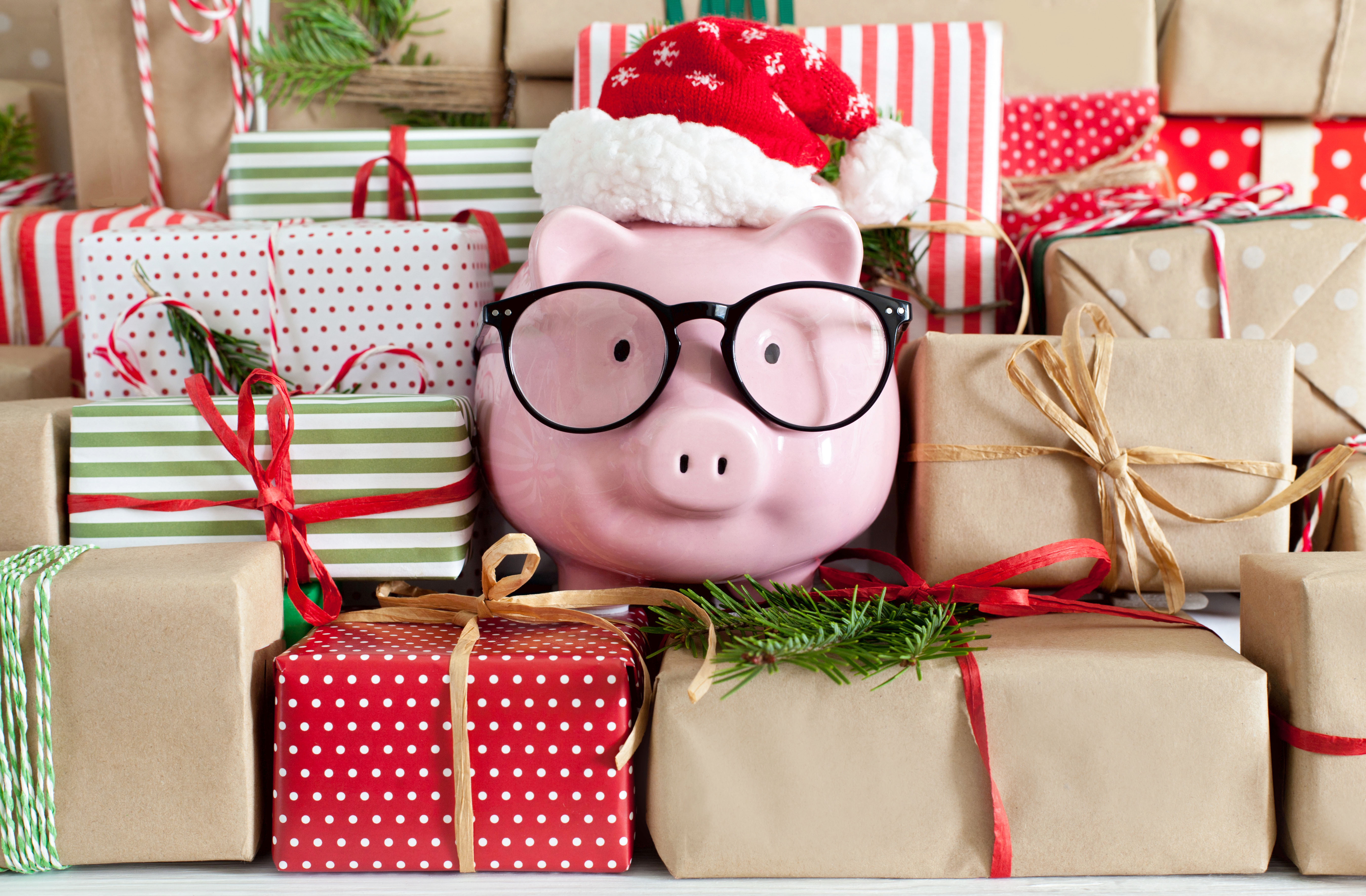Piggy bank with glasses and a Santa hat surrounded by presents