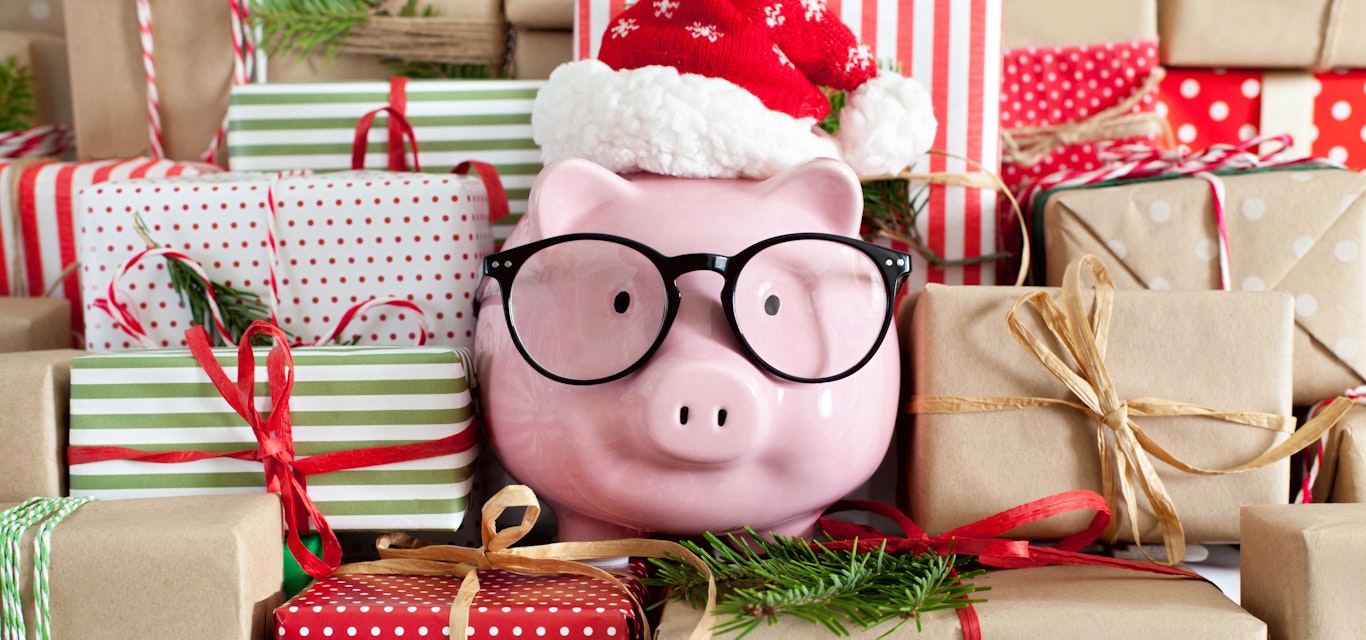 Piggy bank with glasses and a Santa hat surrounded by presents