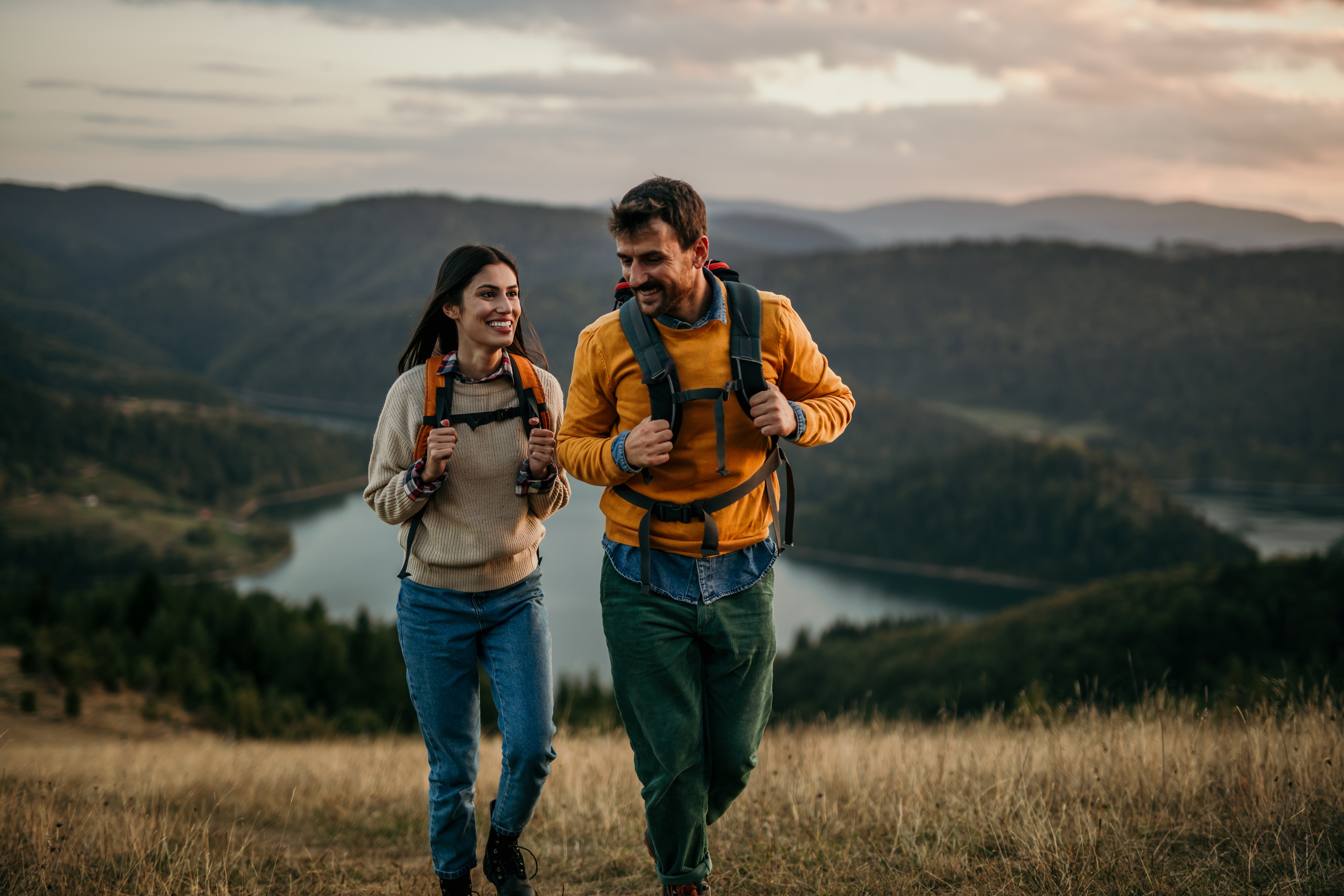 Woman and man hiking up a hill with backpacks