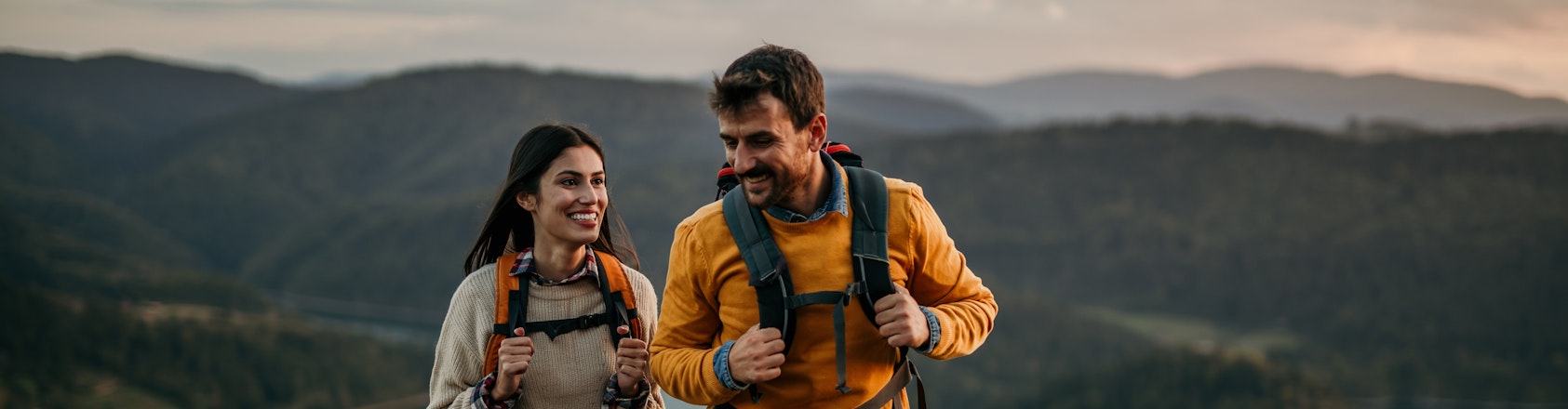 Woman and man hiking up a hill with backpacks