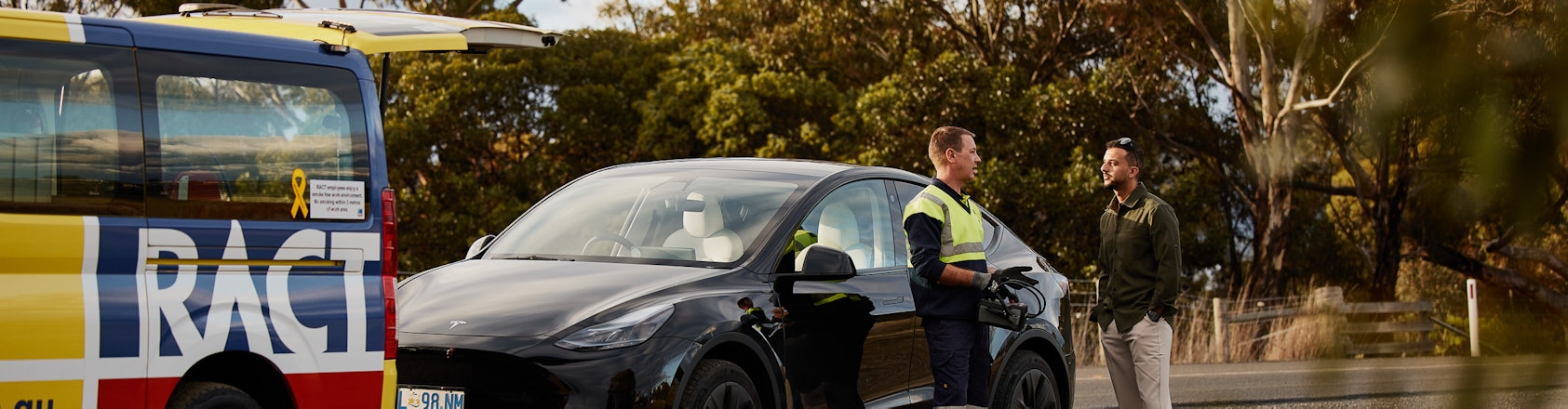 Business woman watching on as roadside patrol changes tyre on her car