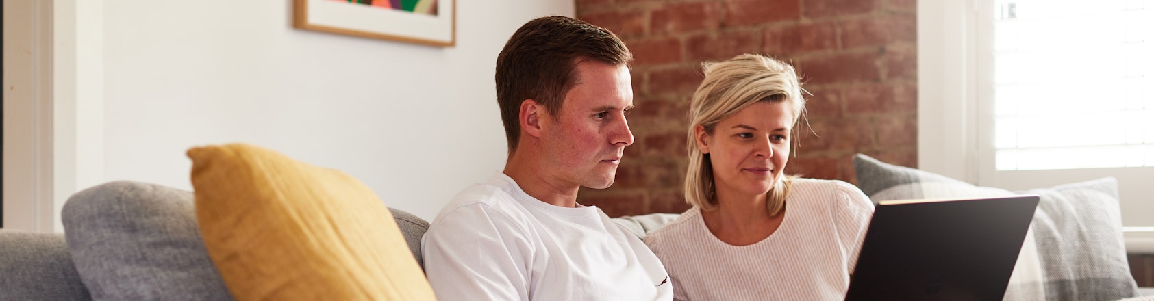 Couple on laptops at dining table.