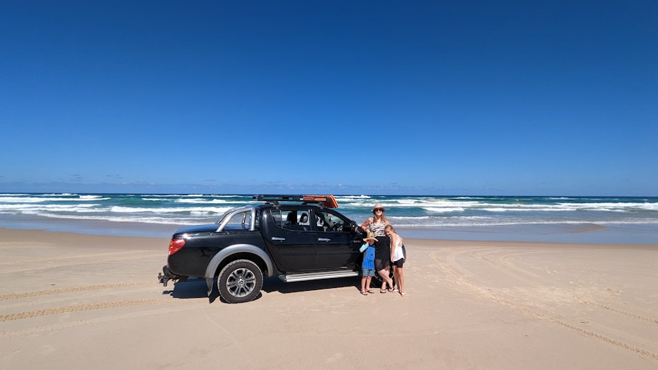 Family on beach standing next to their car