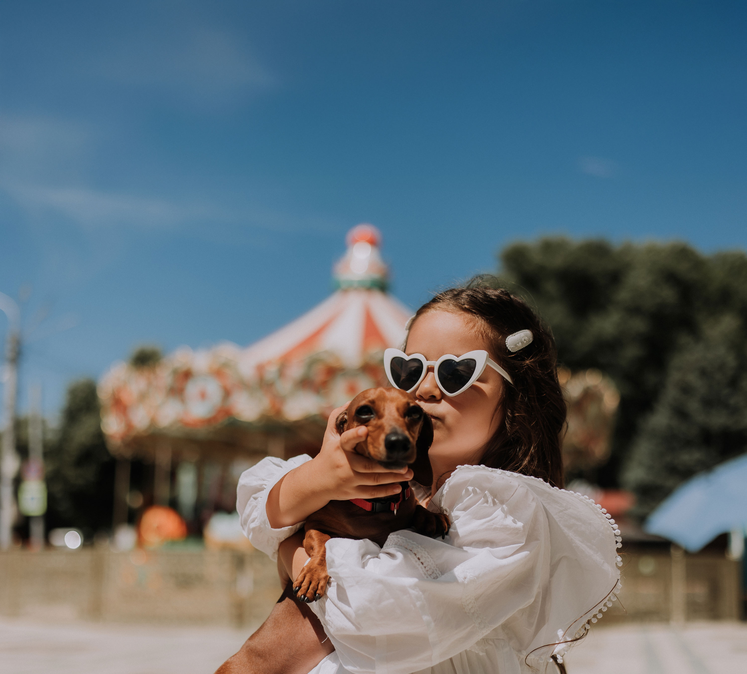 Young girl holding a dachshund dog in front of an event
