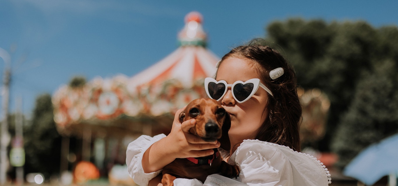 Young girl holding a dachshund dog in front of an event