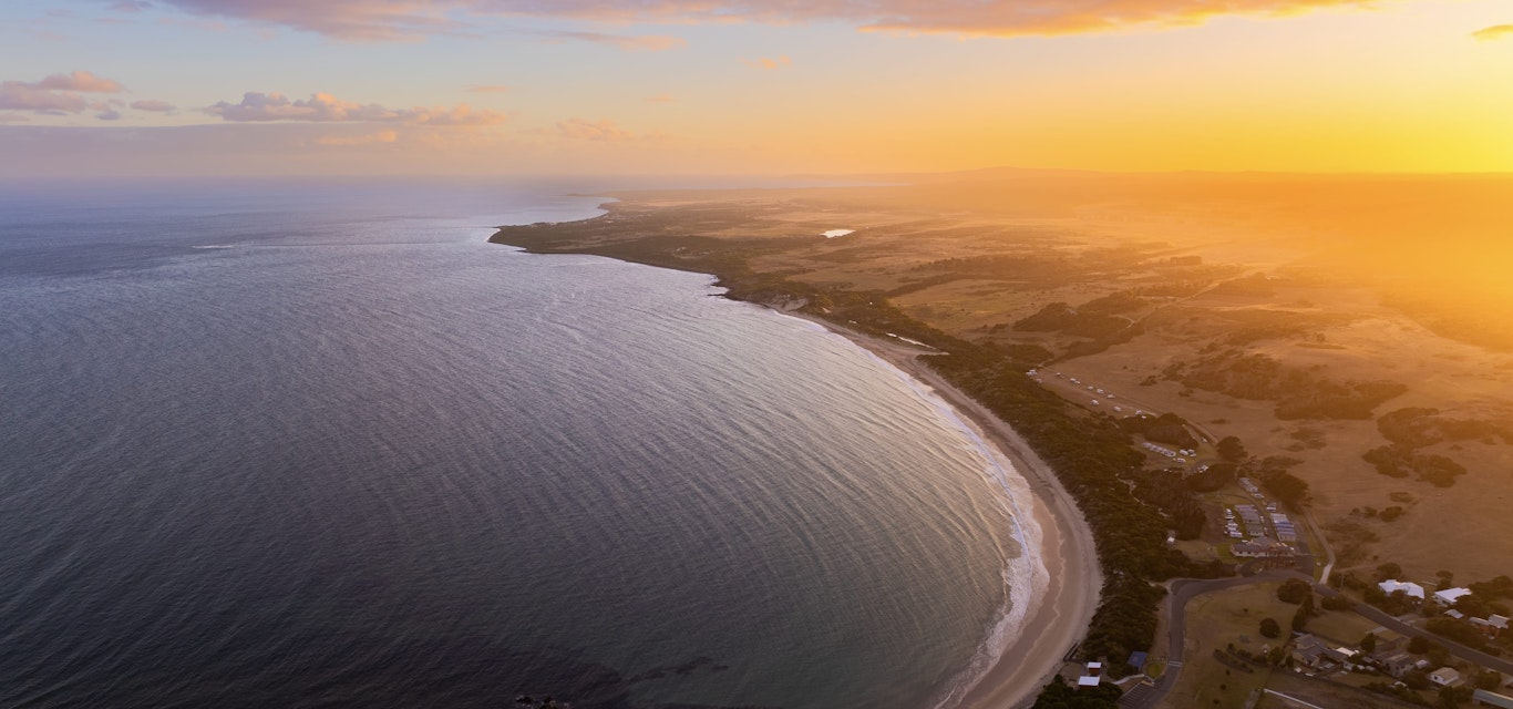 The sun colours East Beach at Low Head.