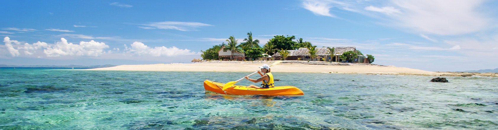 Young woman kayaking near South Sea Island, Mamanuca islands group, Fiji