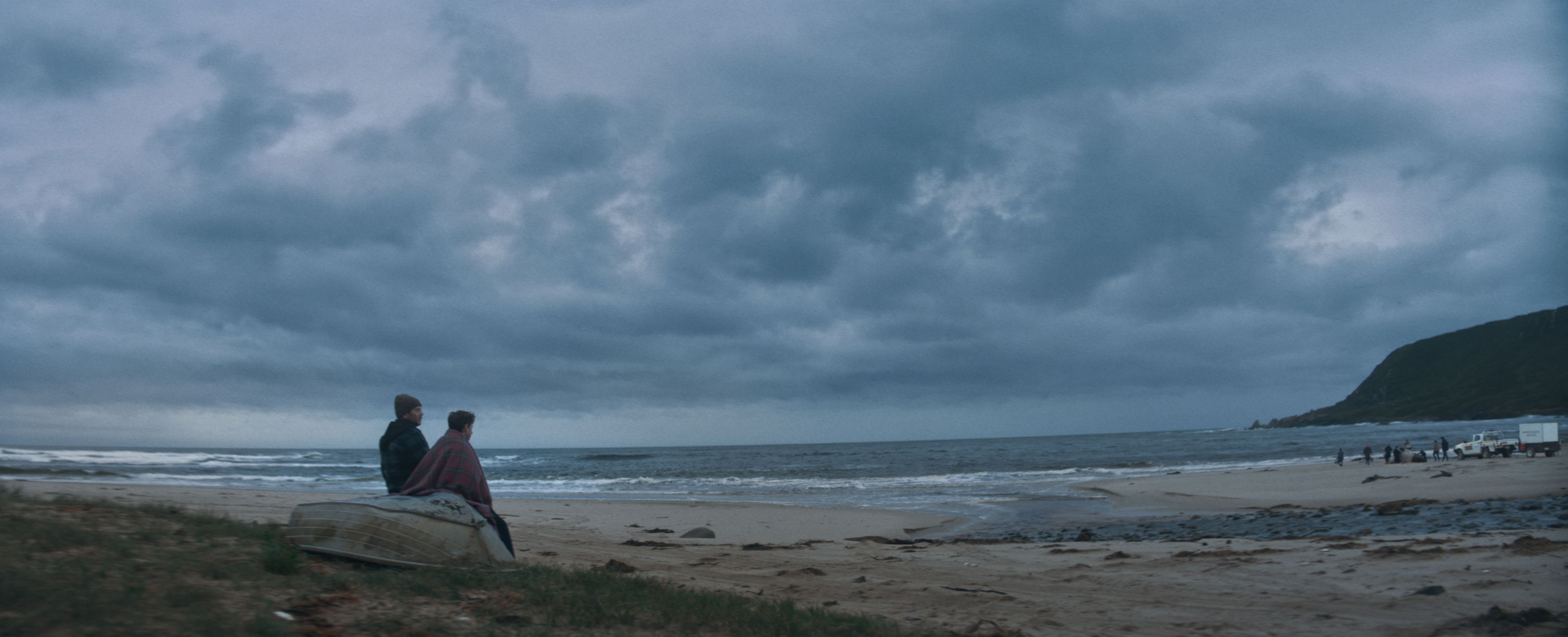 Man and son on beach look out towards the water