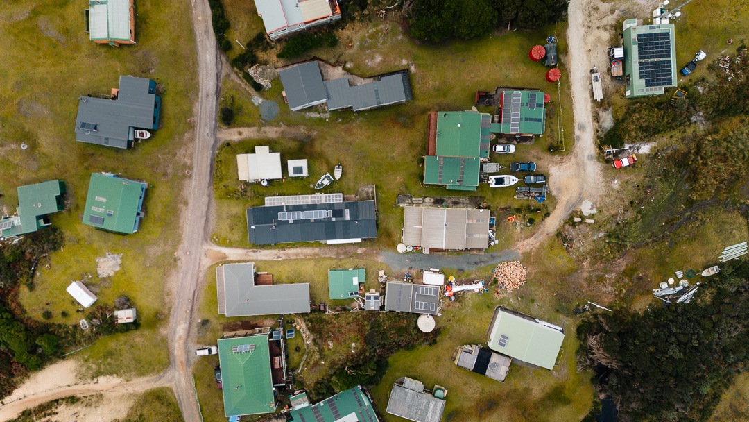 An aerial shot of buildings, cars, caravans and boats in a small community on the West Coast of Tasmania