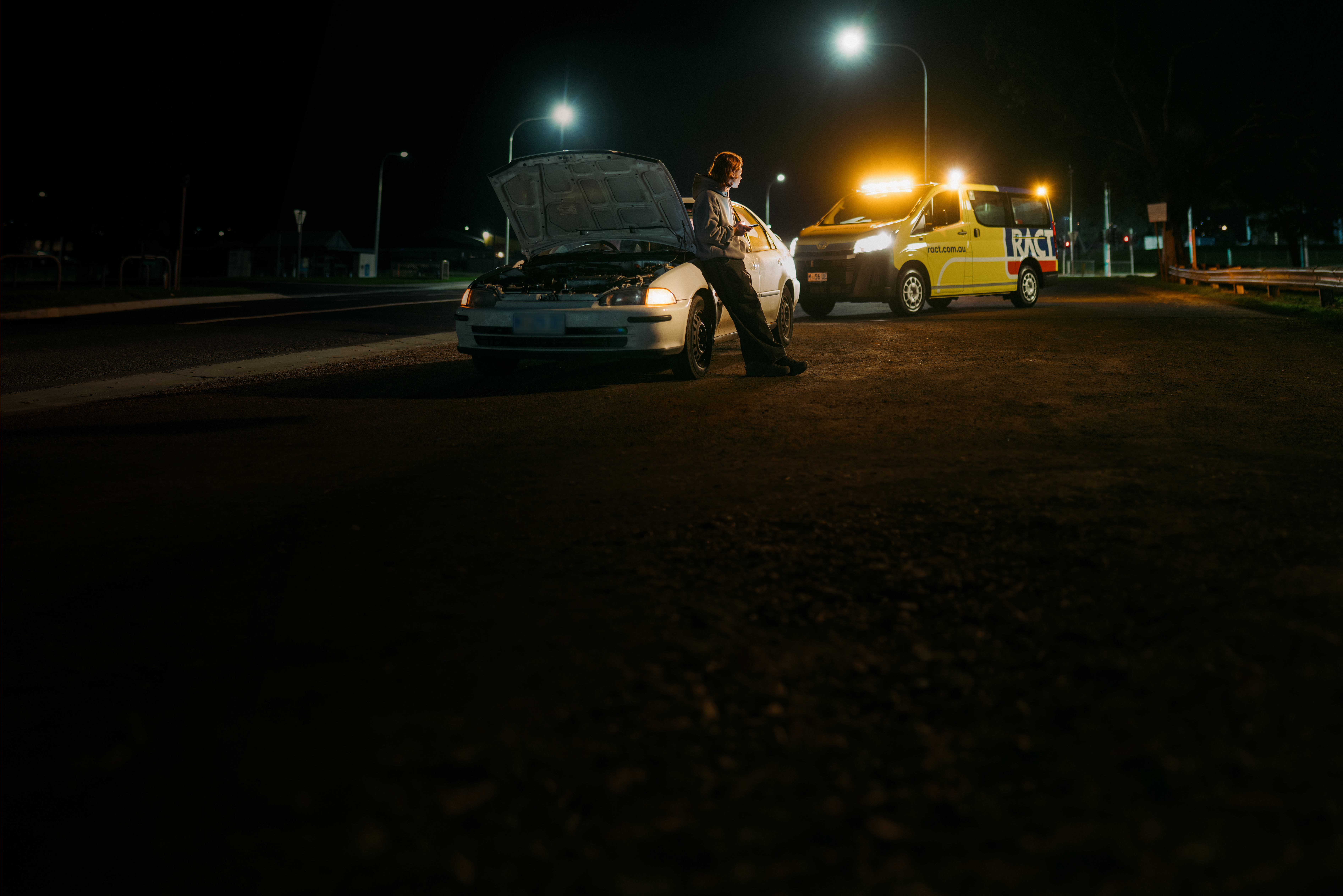 Young man waiting besides his car with RACT Roadside pulling up behind him.