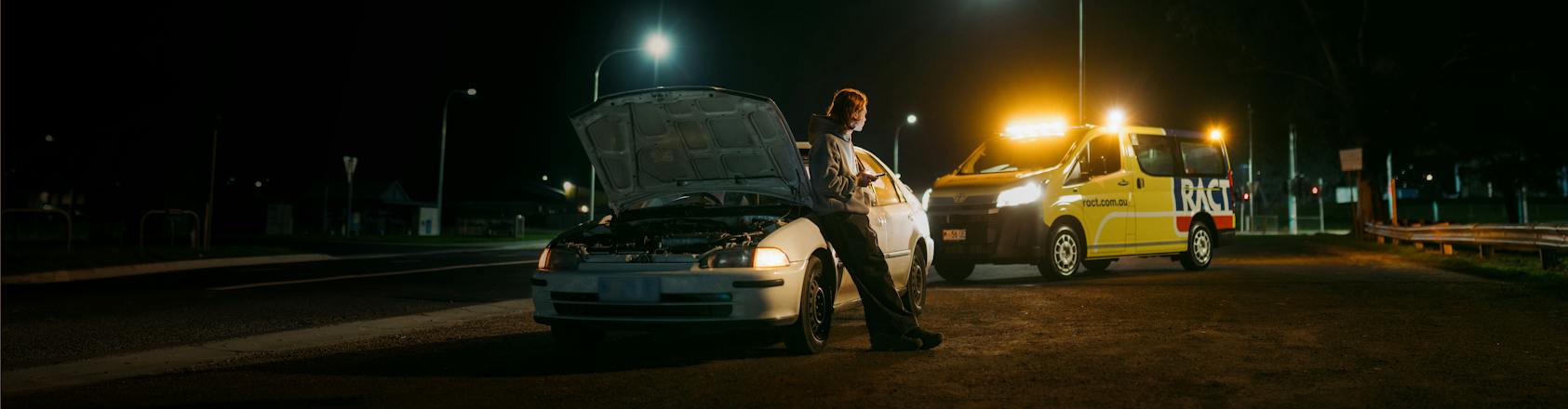 Young man waiting besides his car with RACT Roadside pulling up behind him.