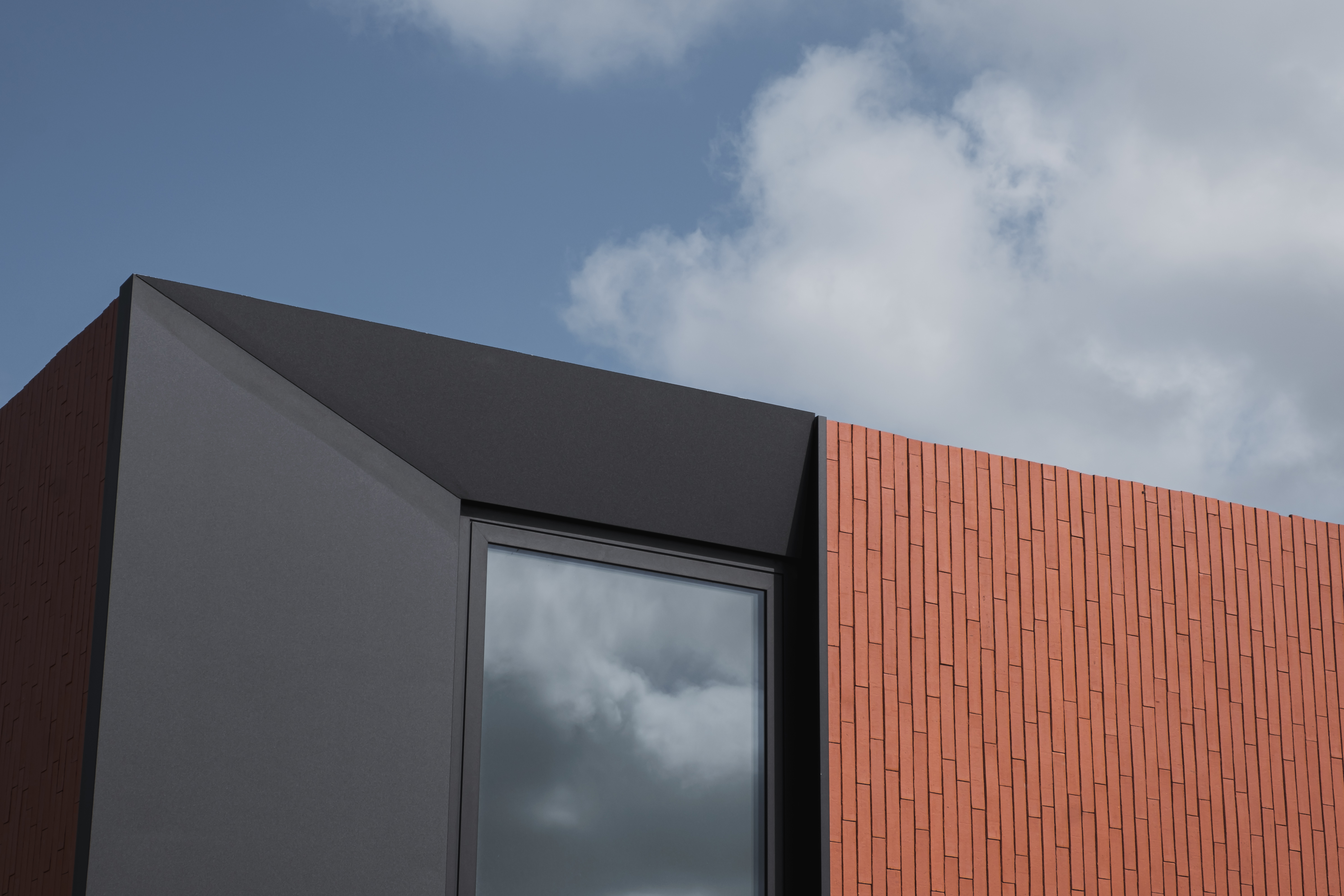 Skilpod modern design houtskeletbouw woning, detail afgeschuind zwart raam en rode steen