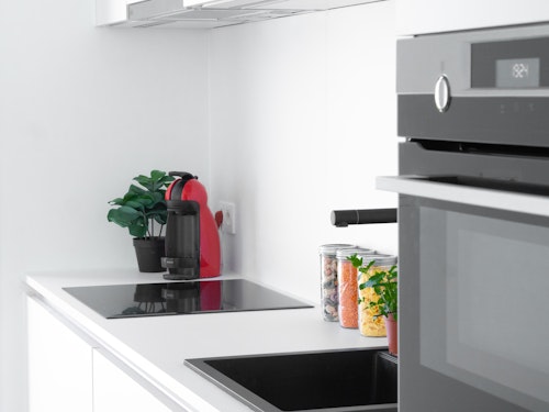 Detail van een Skilpod keuken, zwarte gootsteen en toestellen van AEG: inductiekookplaat, combi-oven, dampkap