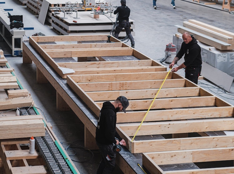 Vakmannen bouwen een prefab element in het Skilpod houtbouw atelier