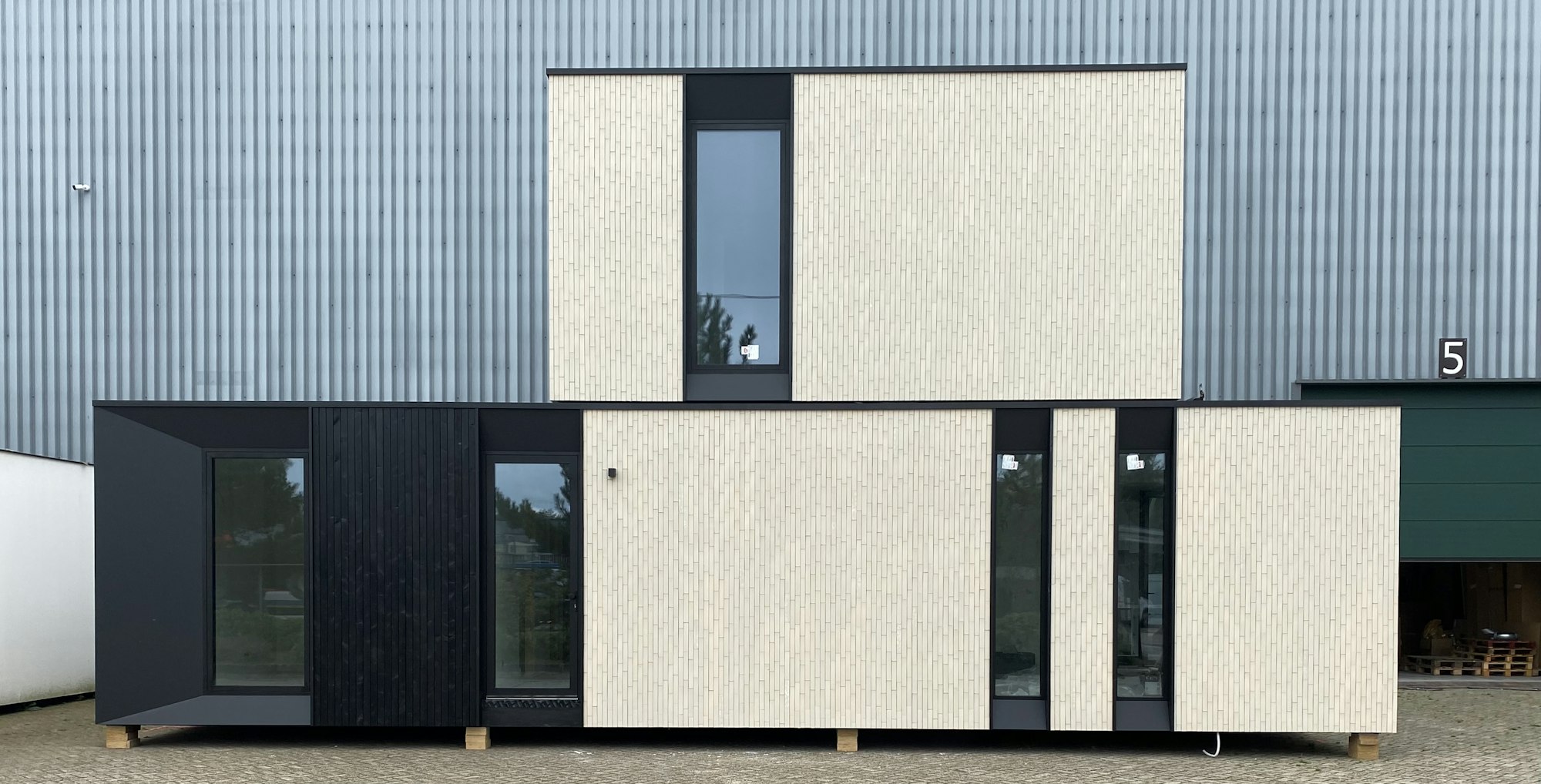 Skilpod #130 — houtskeletbouw woning met 4 slaapkamers, modern design met witte steen en zwart hout