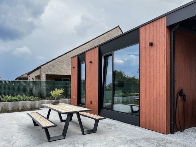 Terras achter een prefab huis van Skilpod in rode steen