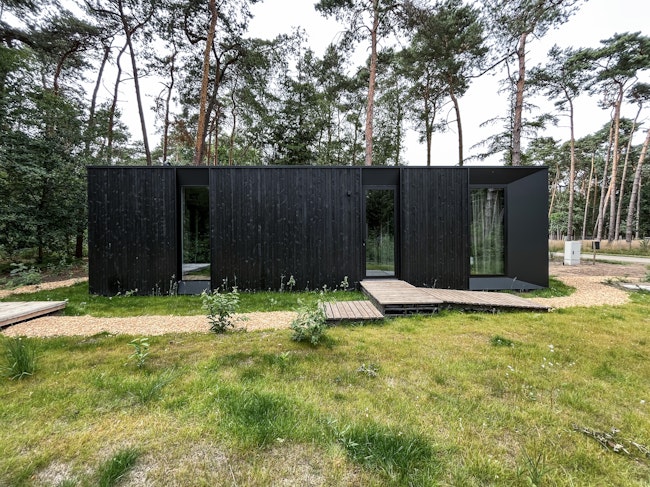 Prefab houtskeletbouw vakantiewoning prototype #80A van Skilpod. Afwerking in zwart hout en zwarte ramen.