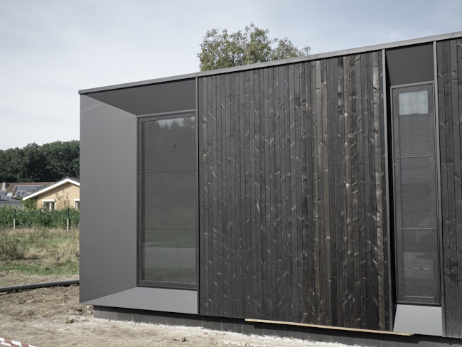 Houtskeletbouw woning Skilpod #100 in zwart hout, recent geplaatst op de bouwwerf
