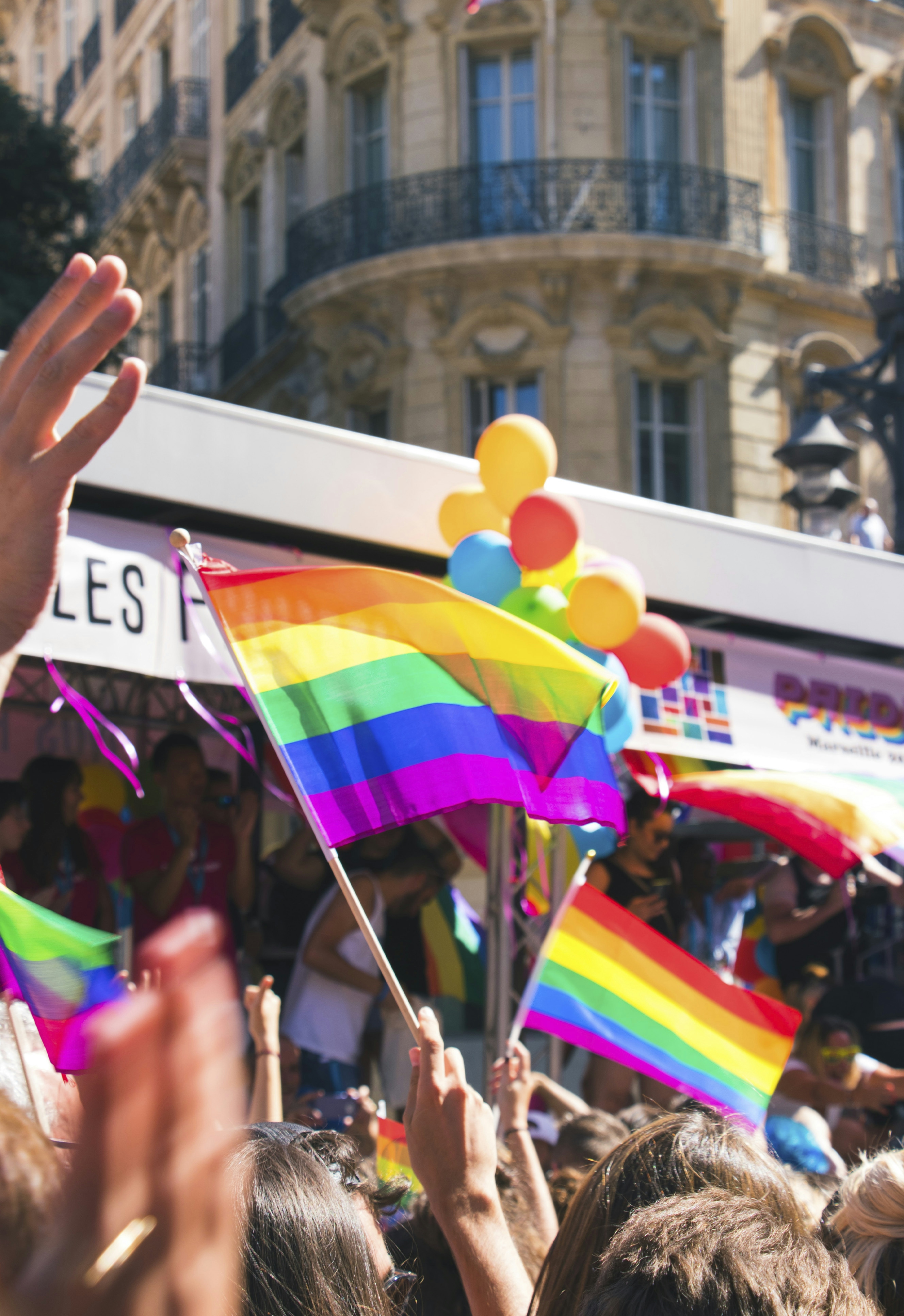 People waving rainbow flags on a street corner