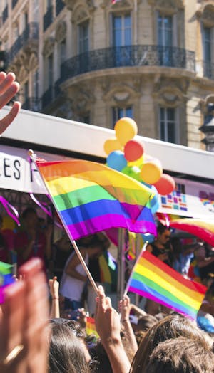 People waving rainbow flags on a street corner