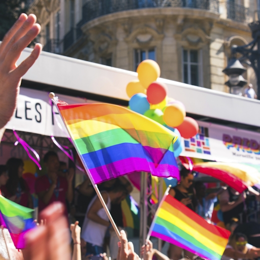 People waving rainbow flags on a street corner