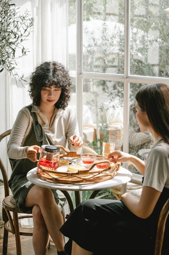 A bright picture of two girls enjoying tea and cake 