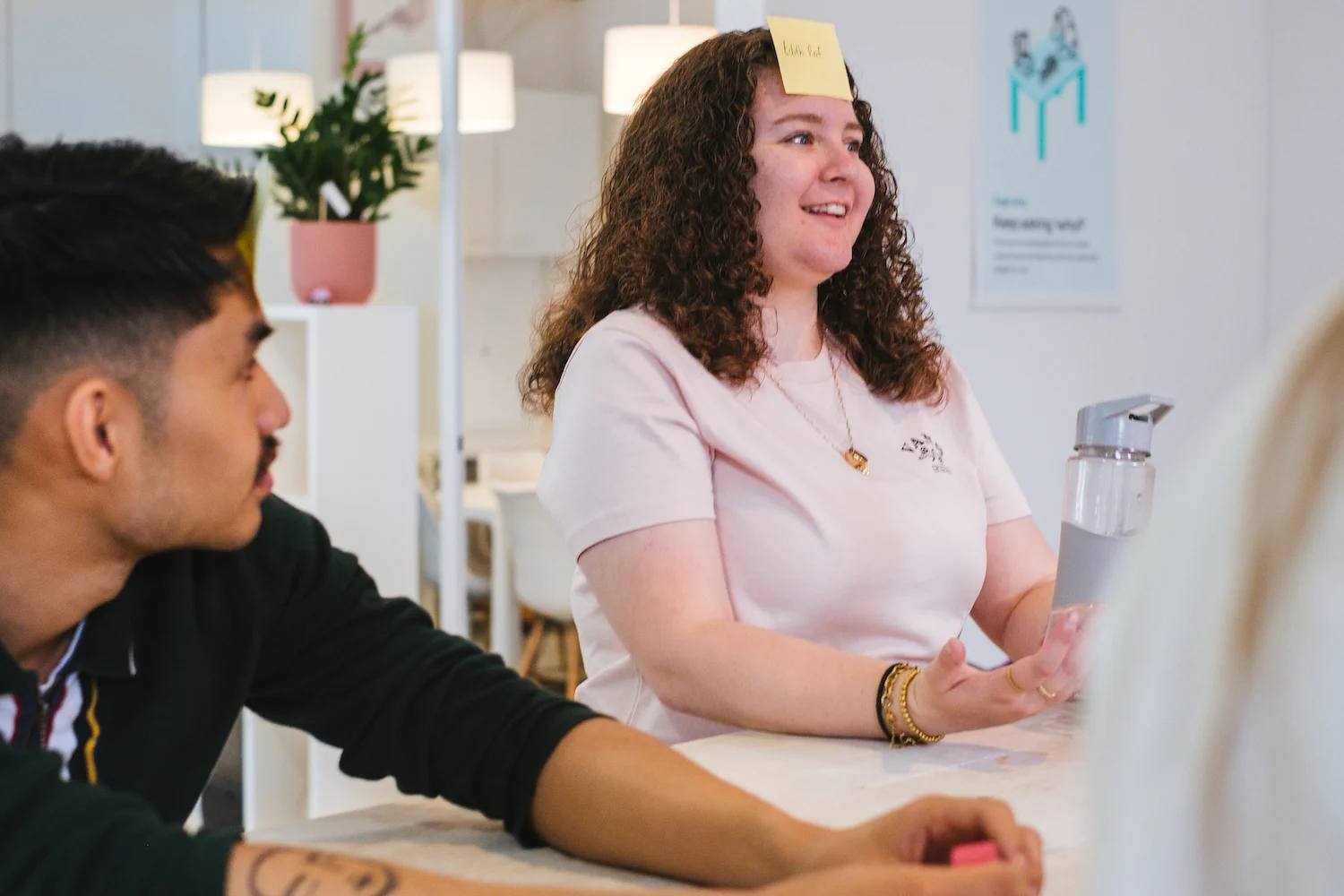 Former UX Design intern Duy looking at UX Designer, and former UX Design intern Cerys as she has a post it stuck to her forehead during a game of Guess Who at the office