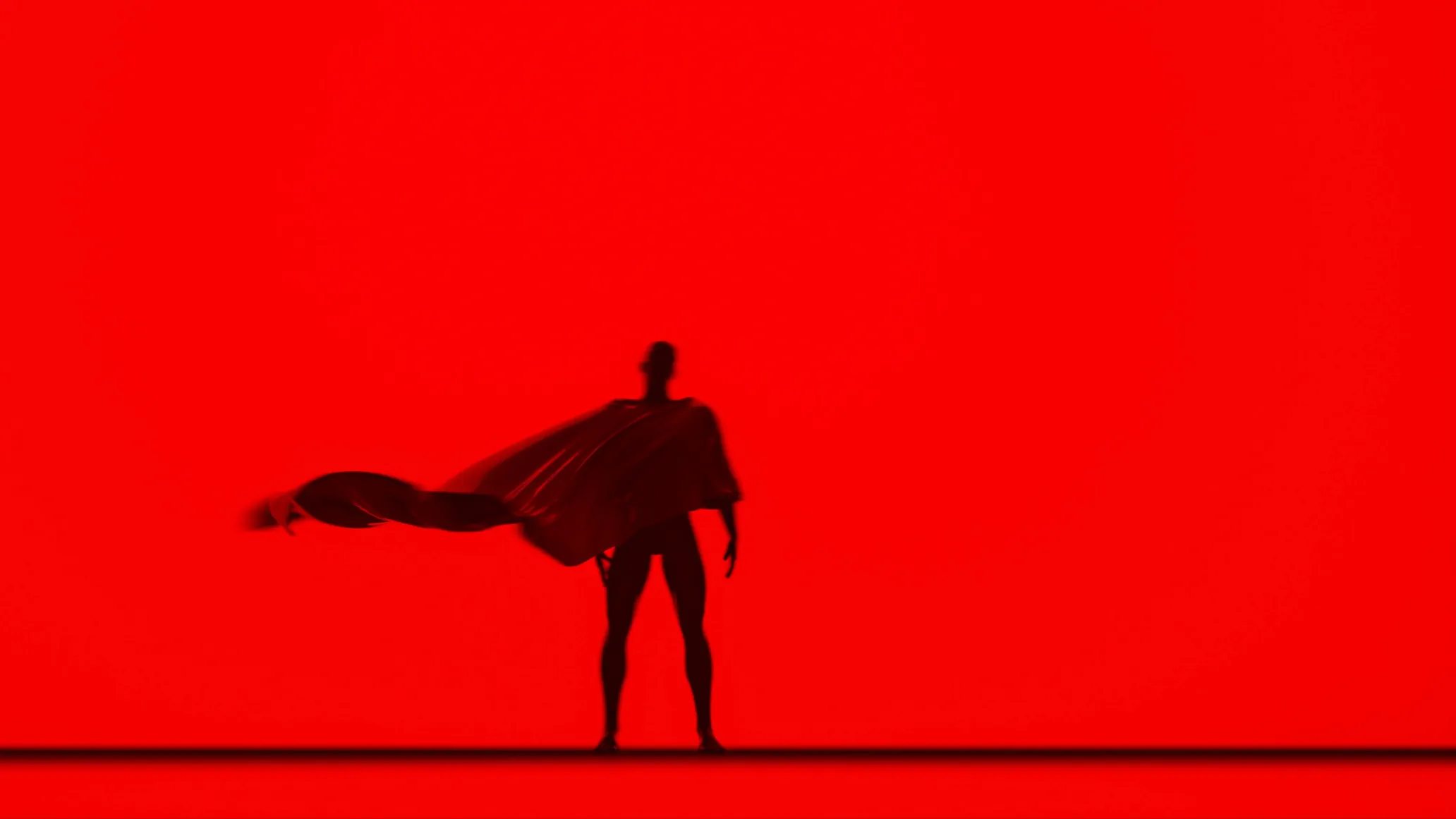 Silhouette of superhero wearing a cape placed on entirely red backdrop.