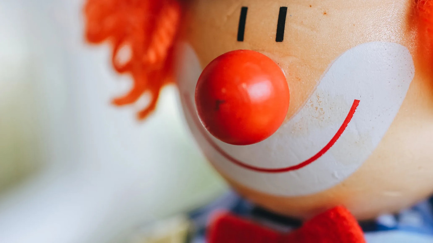 Closeup of a wooden clown doll with its red clowns nose centered