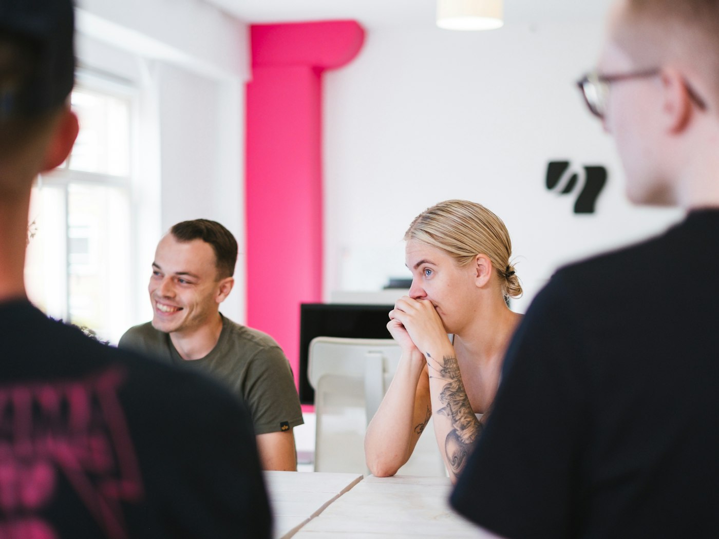 Two people of which one is laughing, both looking in a direction as if listening to someone